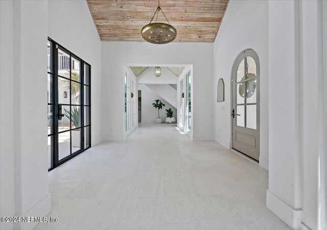 foyer entrance with high vaulted ceiling, french doors, light tile patterned flooring, and wood ceiling