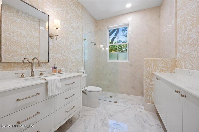 bathroom with tile patterned floors, a tile shower, vanity, and toilet