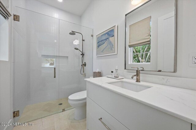 bathroom featuring tile patterned flooring, toilet, an enclosed shower, and vanity