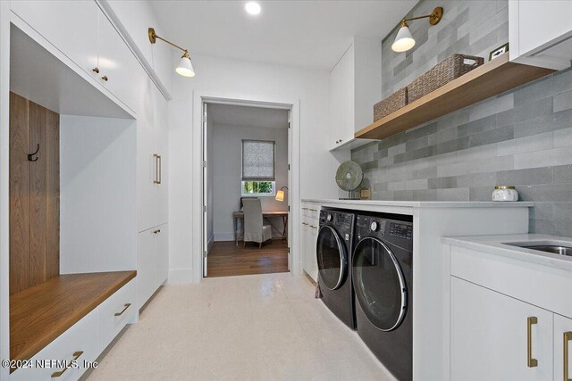 washroom with light tile patterned flooring, separate washer and dryer, and cabinets