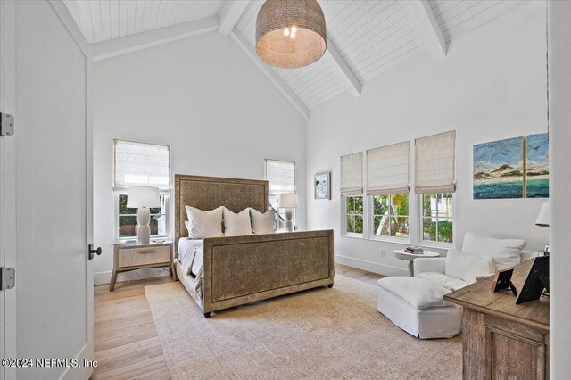 bedroom with high vaulted ceiling, beam ceiling, and light hardwood / wood-style flooring