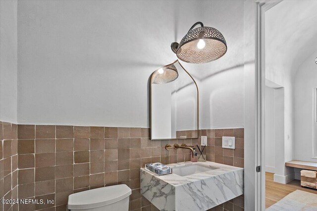 bathroom featuring sink, wood-type flooring, toilet, and tile walls