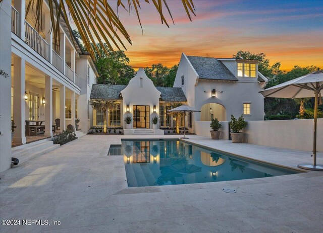 pool at dusk featuring a patio