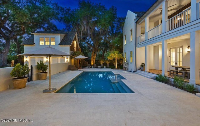 pool at twilight with a patio area