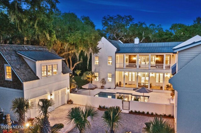 back house at night featuring a garage and a balcony