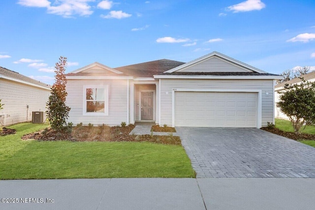 ranch-style house with a front yard, decorative driveway, cooling unit, and an attached garage