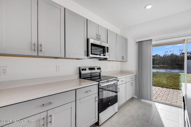 kitchen featuring light tile patterned floors, light countertops, appliances with stainless steel finishes, and a water view