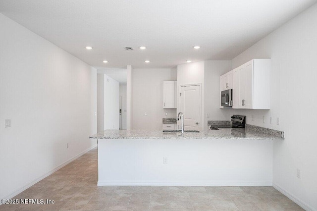 kitchen with light stone counters, stainless steel appliances, a peninsula, and visible vents