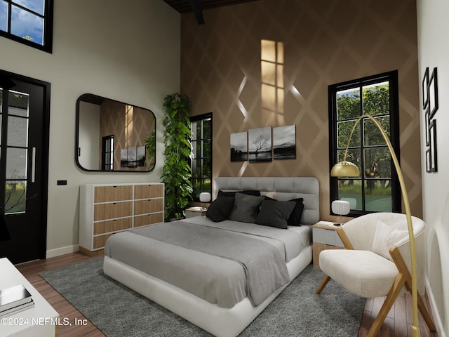 bedroom featuring hardwood / wood-style flooring and a towering ceiling