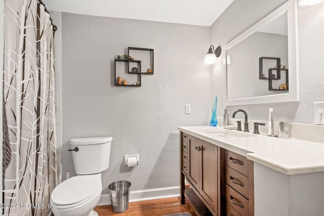 bathroom with hardwood / wood-style flooring, toilet, and vanity