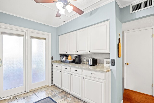 kitchen featuring backsplash, crown molding, white cabinets, ceiling fan, and light tile patterned flooring