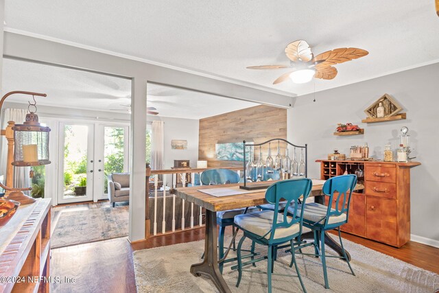 dining space featuring ceiling fan, wood walls, light wood-type flooring, and a textured ceiling