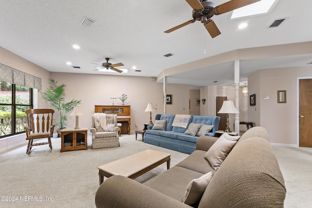 living room featuring a textured ceiling, a skylight, ceiling fan, and carpet