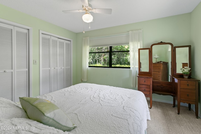 carpeted bedroom featuring ceiling fan and two closets