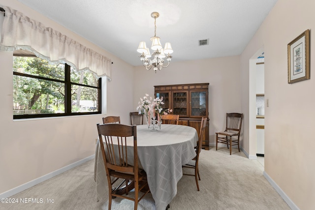 dining space featuring light carpet and an inviting chandelier