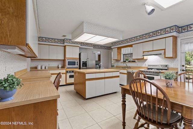 kitchen featuring stainless steel appliances, light tile patterned floors, and white cabinetry