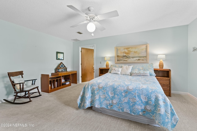 carpeted bedroom featuring ceiling fan and a textured ceiling