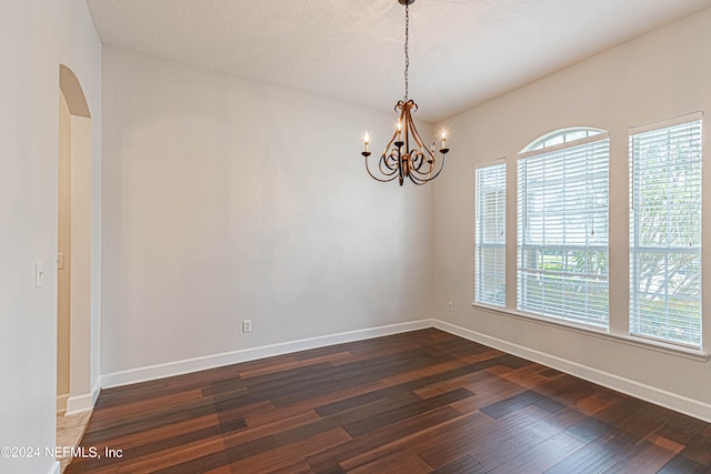 spare room with dark hardwood / wood-style floors, an inviting chandelier, and a textured ceiling