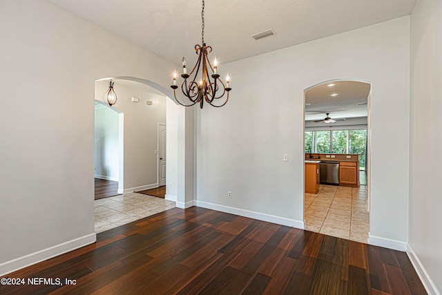 unfurnished dining area featuring ceiling fan with notable chandelier, a textured ceiling, and light hardwood / wood-style floors