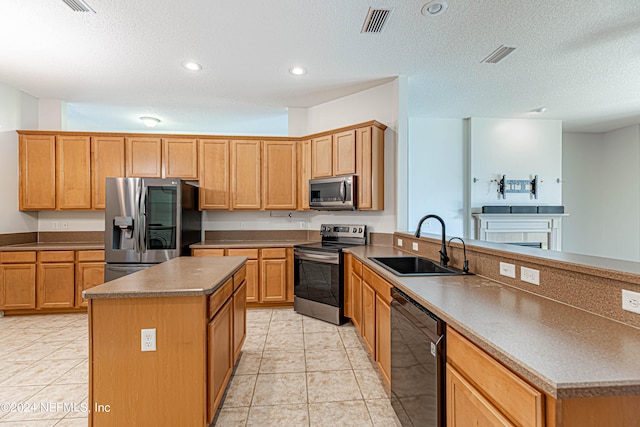 kitchen featuring a textured ceiling, a kitchen island, light tile patterned floors, stainless steel appliances, and sink