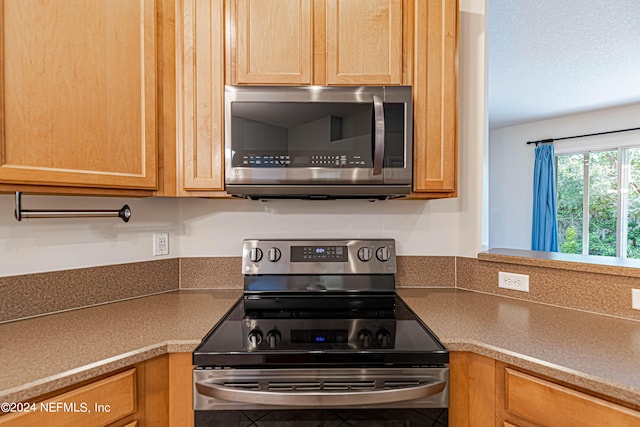 kitchen with a textured ceiling and appliances with stainless steel finishes