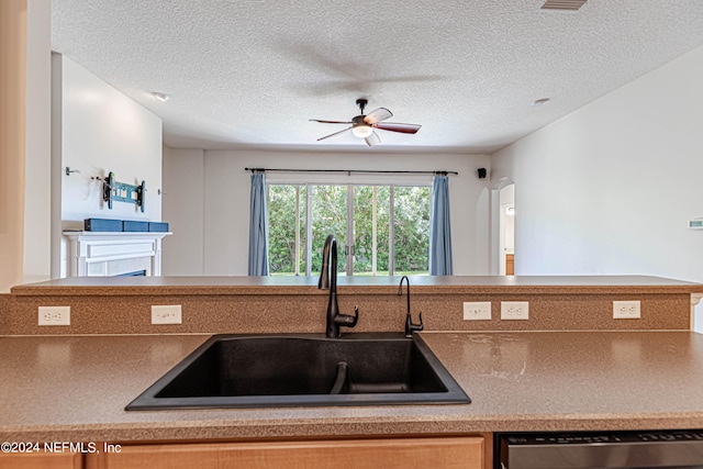 kitchen featuring ceiling fan, dishwasher, sink, and a textured ceiling