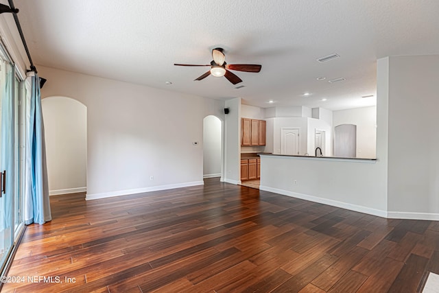 unfurnished living room featuring dark hardwood / wood-style flooring, ceiling fan, and a textured ceiling