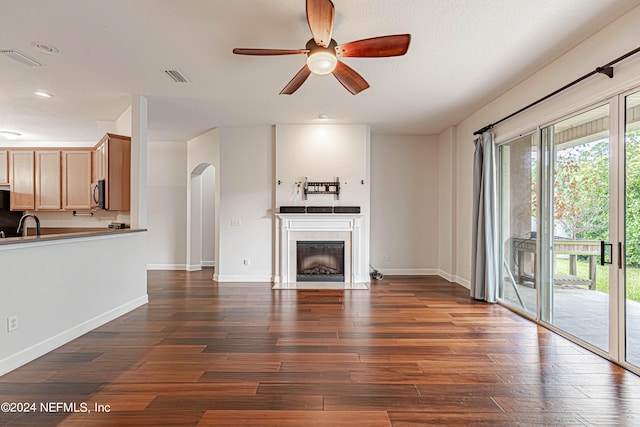 unfurnished living room with plenty of natural light, ceiling fan, a tile fireplace, and dark hardwood / wood-style flooring