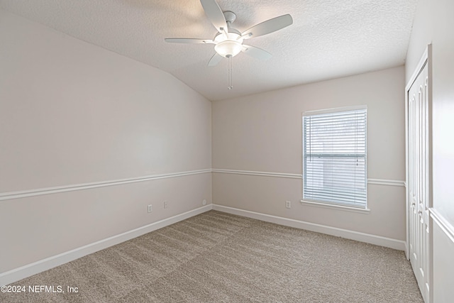 empty room featuring carpet, a textured ceiling, ceiling fan, and lofted ceiling