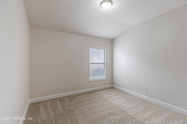 carpeted spare room featuring a textured ceiling and vaulted ceiling