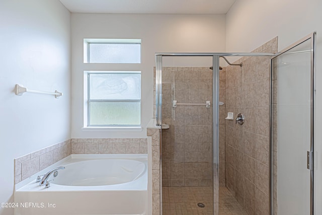 bathroom with a wealth of natural light and shower with separate bathtub