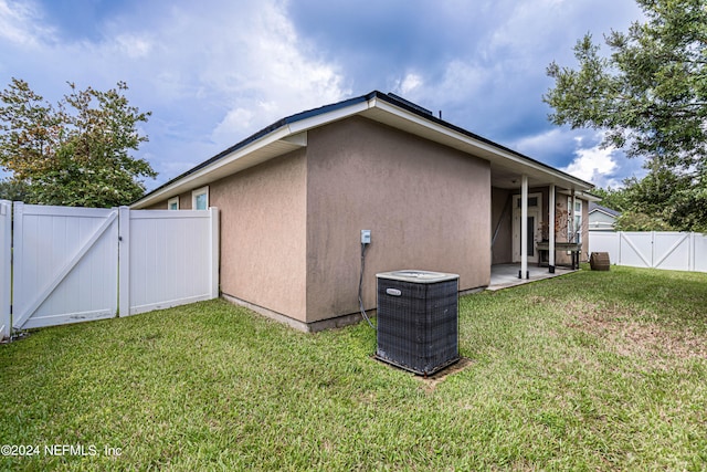 view of side of home with central air condition unit, a yard, and a patio area