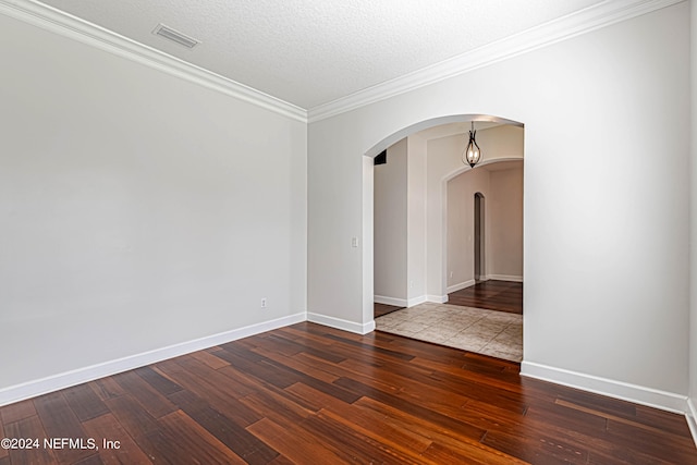 unfurnished room featuring dark wood-type flooring, a textured ceiling, and ornamental molding