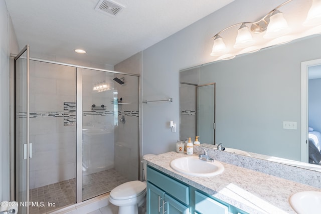 bathroom featuring vanity, toilet, tile patterned flooring, and a shower with door