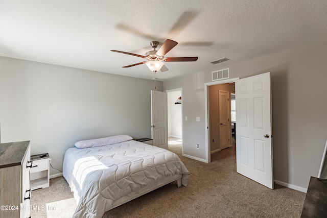 carpeted bedroom featuring ceiling fan and a textured ceiling