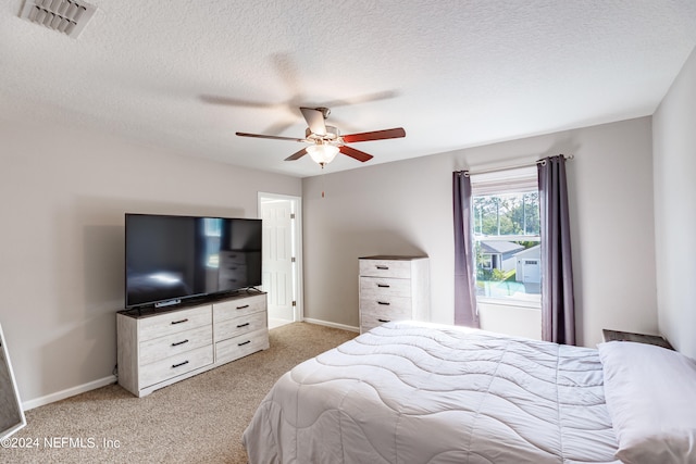 bedroom featuring ceiling fan, light carpet, and a textured ceiling