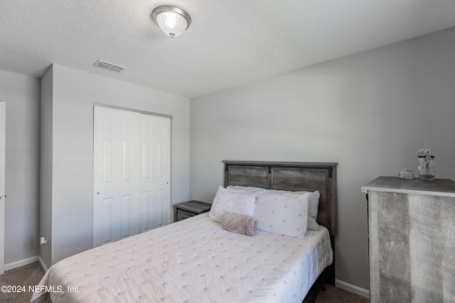 carpeted bedroom featuring a textured ceiling and a closet