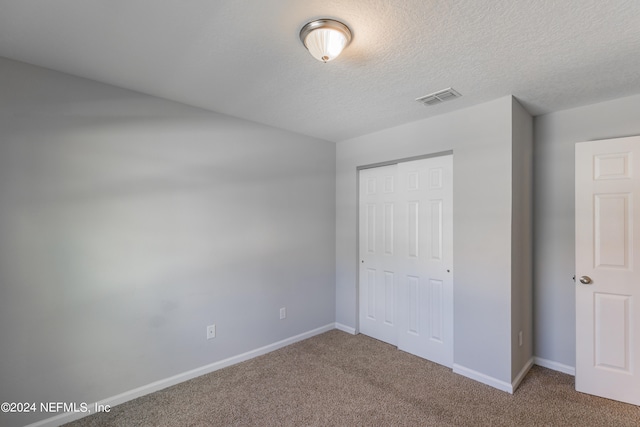 unfurnished bedroom featuring a textured ceiling, carpet, and a closet