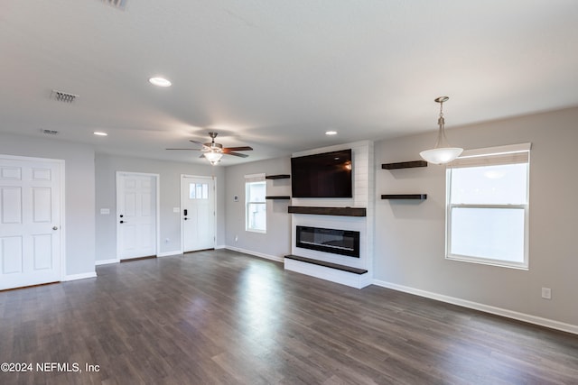 unfurnished living room with dark wood-type flooring, ceiling fan, and a fireplace