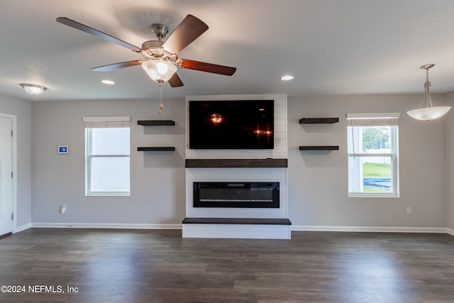 unfurnished living room with a large fireplace, ceiling fan, and dark hardwood / wood-style flooring