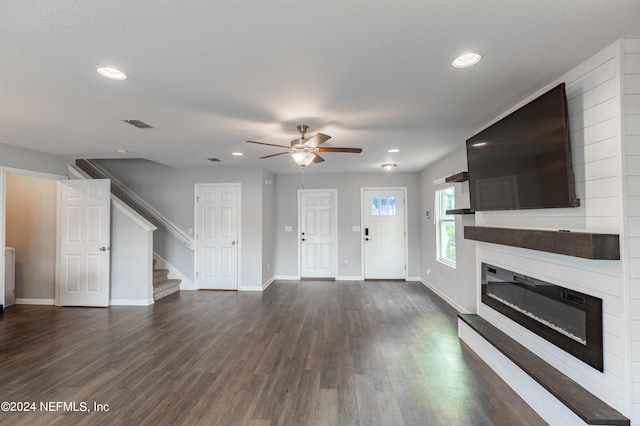 unfurnished living room featuring ceiling fan, a fireplace, and dark hardwood / wood-style floors