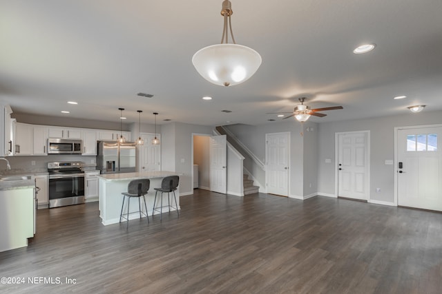 kitchen with dark wood-type flooring, a center island, stainless steel appliances, and ceiling fan