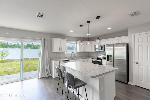 kitchen with pendant lighting, white cabinetry, stainless steel appliances, dark hardwood / wood-style flooring, and a kitchen island