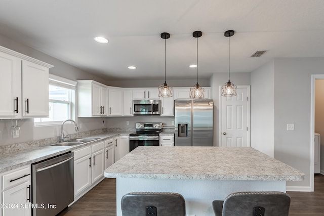 kitchen with dark hardwood / wood-style flooring, a kitchen island, stainless steel appliances, and sink