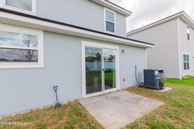 back of property with central AC unit and a patio area