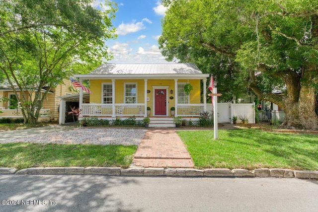 bungalow-style house with covered porch, metal roof, a front lawn, and fence