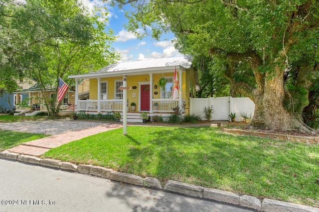 bungalow with metal roof, covered porch, a front yard, and fence