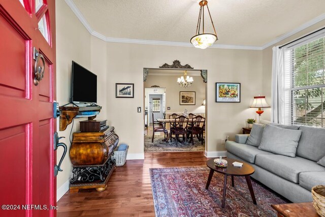 living room with crown molding, dark hardwood / wood-style floors, and a notable chandelier