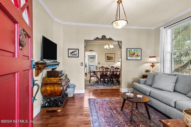 living room featuring dark wood-type flooring, baseboards, crown molding, and an inviting chandelier