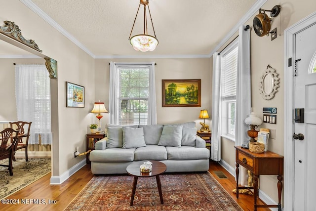 living area with visible vents, a textured ceiling, wood finished floors, and crown molding